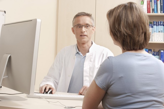 Arzt und Patientin vor einem PC-Monitor