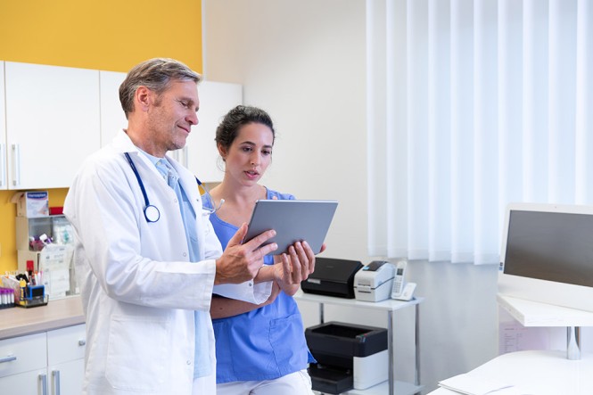 Arzt und Krankenschwester schauen auf ein Tablet