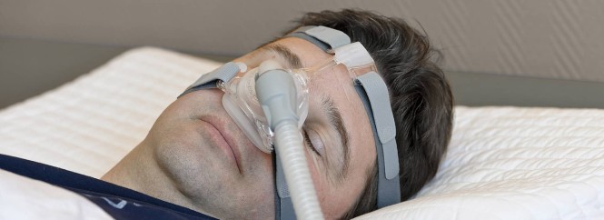 Schlafender Mann mit einem Gerät zur nächtlichen Überdruckatmung
