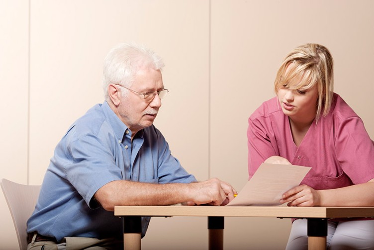 Jüngere Frau und älterer Mann am Tisch mit Formularen
