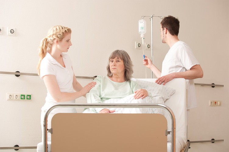 Eine Pflegerin betreut eine Patientin in einem Krankenhausbett