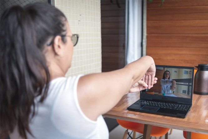 Eine Frau macht Dehnübungen vor ihrem Laptop