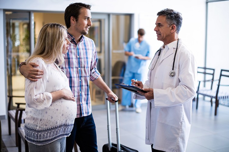 Ein Arzt im Krankenhaus spricht mit einer schwangeren Frau und ihrem Partner