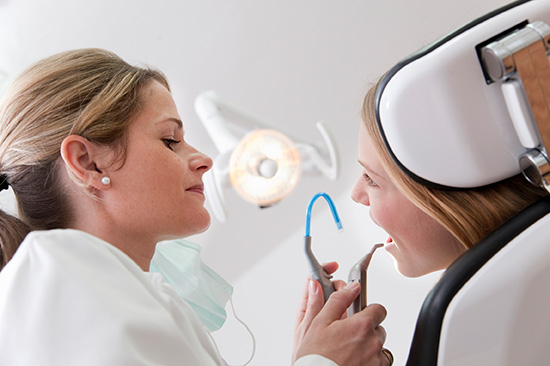 Eine Zahnärztin untersucht den Mund einer Patientin