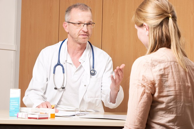 Ein Arzt spricht in seiner Praxis mit einer Patientin.