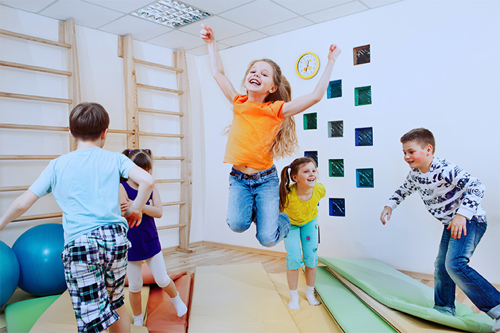 Mehrere Kinder springen ausgelassen in einer Sporthalle