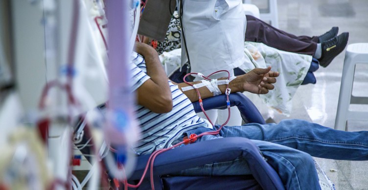 Ein Mann, dessen Gesicht man nicht sieht, sitzt im Krankenhaus an einer Dialyse-Maschine.